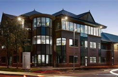 Photo of a multi-story office building at dusk with interior lights on and a street in the foreground